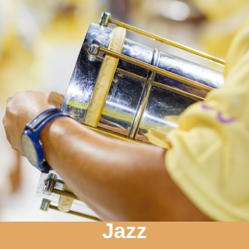 You can see the art of a person with brown skin and a yellow shirt holding a silver metal drum. Genre label reads, "jazz."